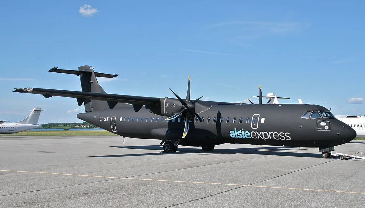 A dark Alsie Express airplane parked at an airport apron.